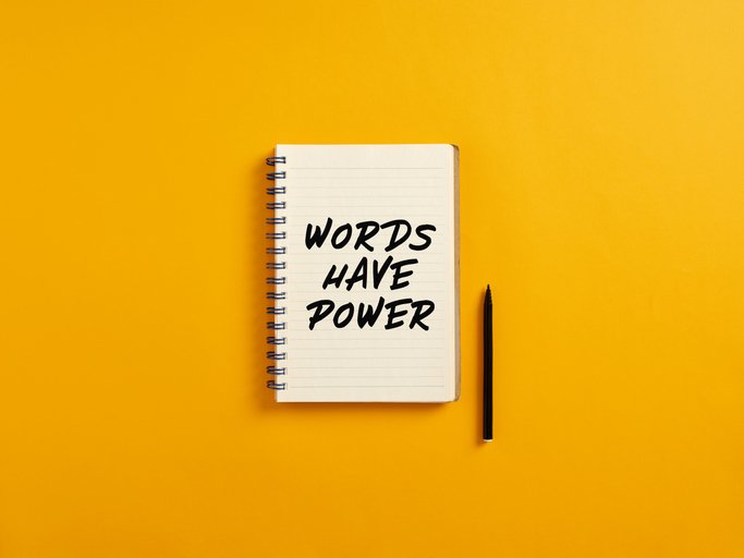 Notebook reading “Words Have Power” beside a pencil on a yellow background