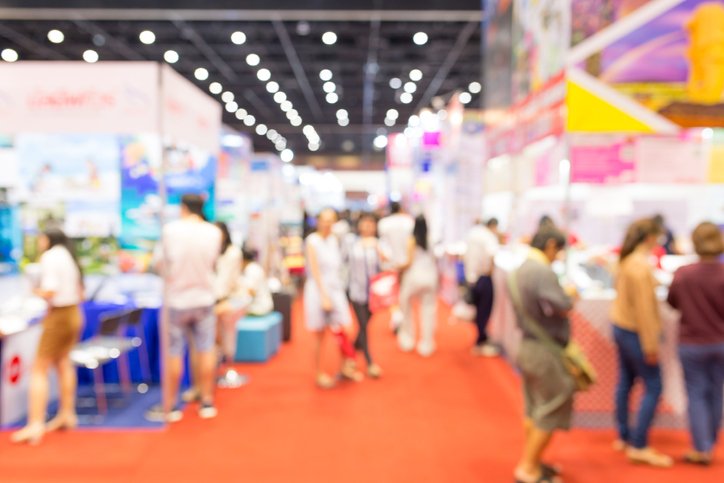 Visitors walking between exhibition booths at a trade show