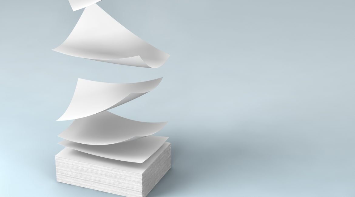 Sheets of white paper floating above a neatly stacked ream